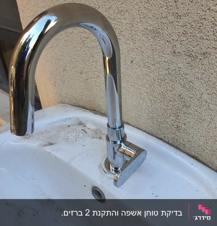 ברז כרום מותקן על כיור לבן עם לכלוך